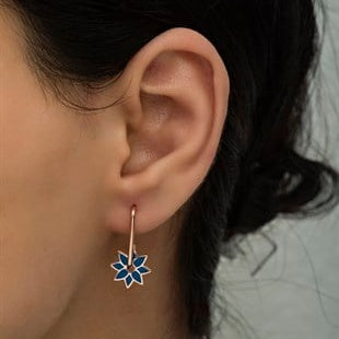 Close-up of an ear wearing a floral earring with a blurred background