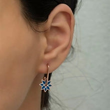 Close-up of an ear wearing a floral earring with a blurred background