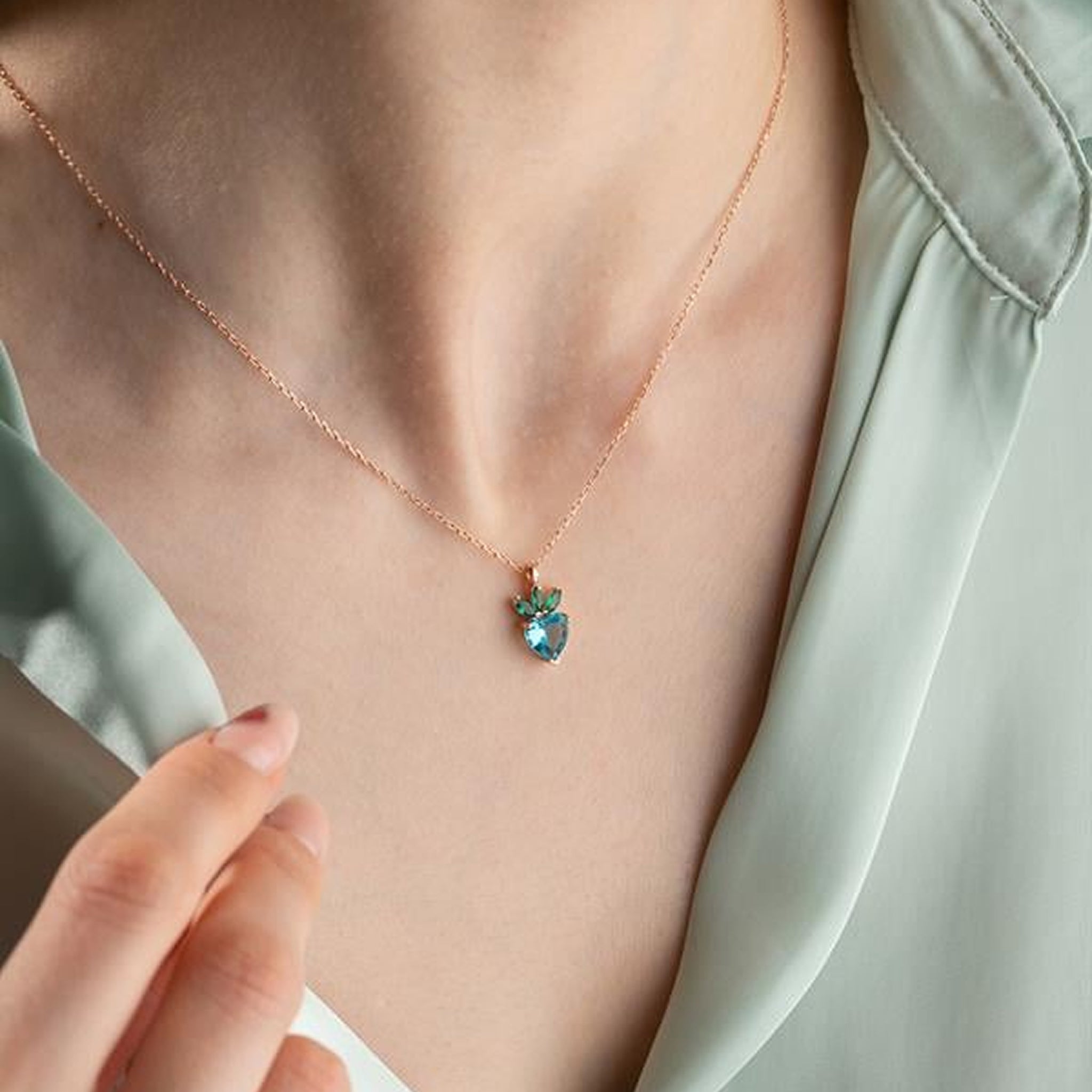 Necklace with a green pendant worn by a person, against a light background