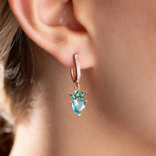Close-up of an earring with a heart-shaped gemstone worn by a person.