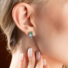 Close-up of an ear wearing a turquoise heart-shaped earring with a blurred background
