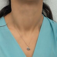 Necklace with a pendant worn by a person in a light blue top against a neutral background