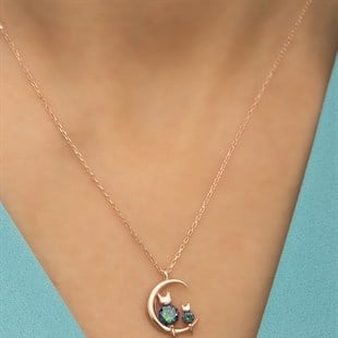 Necklace with a cat and moon pendant on a person's neck against a blue background