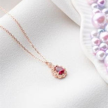 Rose gold necklace with a pink gemstone on a white surface