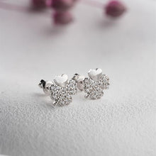 Silver four-leaf clover earrings on a light gray background