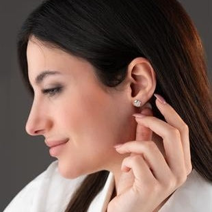 Woman adjusting an earring with a close-up of her ear.