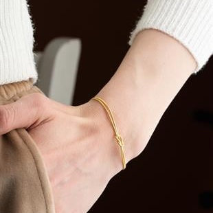 Close-up of a wrist wearing a gold bracelet with a blurred background