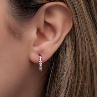 Close-up of an ear wearing a diamond earring with a blurred background