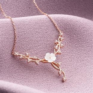 Rose gold necklace with floral design on a pink fabric background