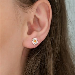 Close-up of an ear wearing a daisy flower earring with a neutral background