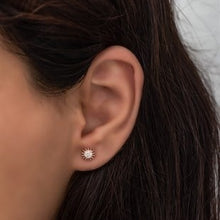 Close-up of an ear wearing a diamond earring with dark hair.
