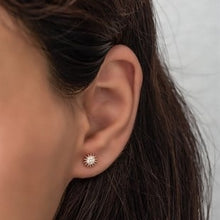 Close-up of an ear wearing a star-shaped earring with a neutral background