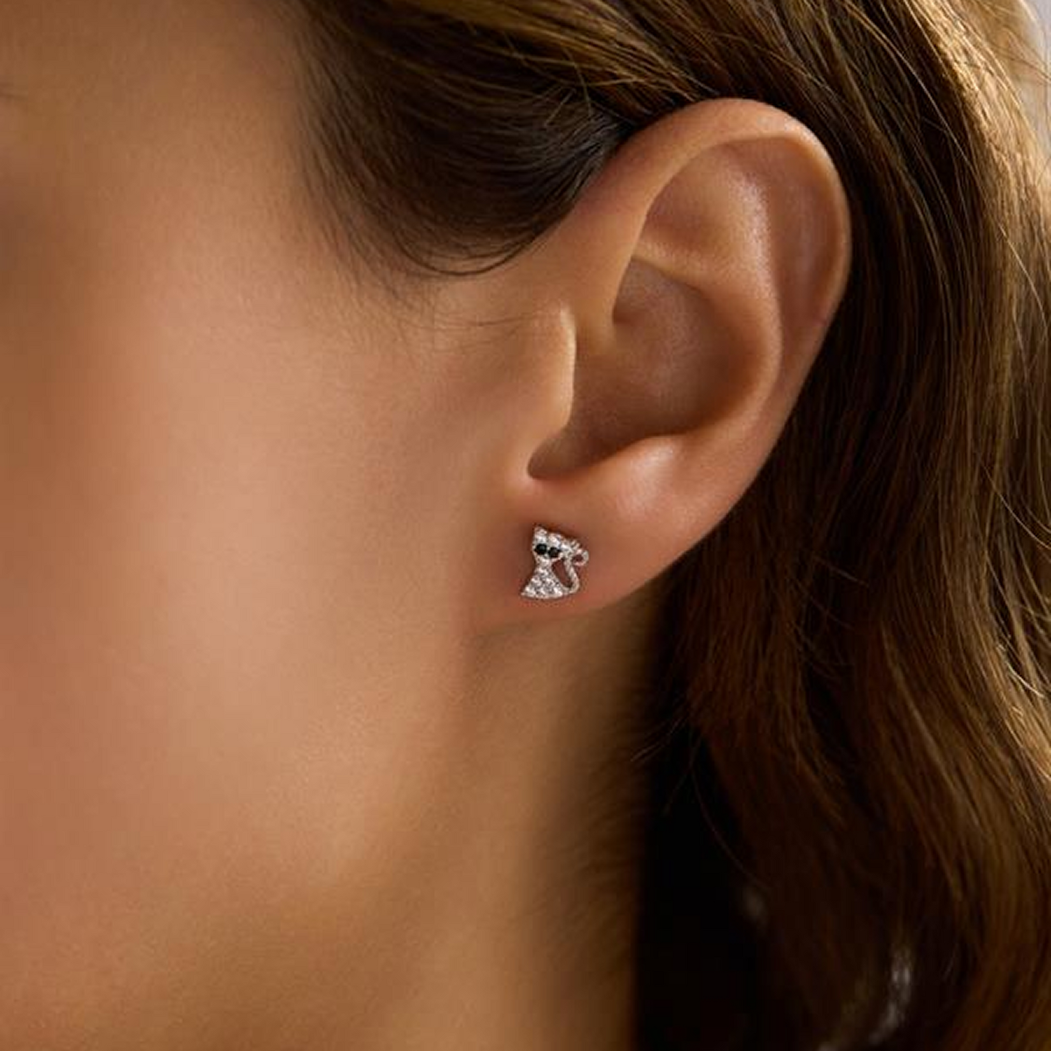 Close-up of an ear wearing a diamond earring with a blurred background
