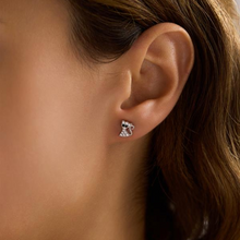Close-up of an ear wearing a diamond earring with a blurred background