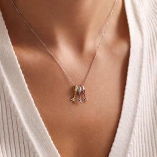 Necklace with a pendant worn by a person in a white outfit