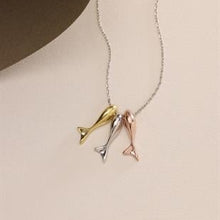 Necklace with three fish-shaped pendants on a beige background