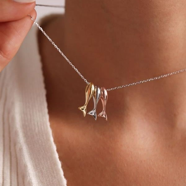 Necklace with gold and silver fish pendants on a blurred background