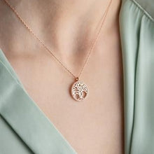 Rose gold tree-shaped pendant necklace on a person wearing a light green garment.
