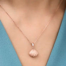 Rose gold necklace with a shell pendant on a mannequin against a blue background