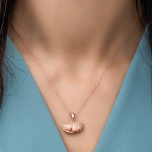 Rose gold necklace with a pendant on a person wearing a blue top