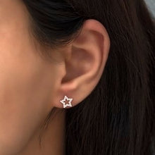 Close-up of an ear wearing a star-shaped earring with dark hair.