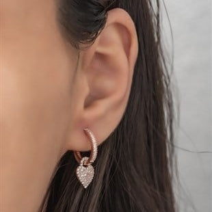Close-up of an ear wearing a heart-shaped earring with a blurred background