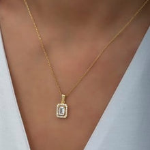 Gold necklace with a diamond pendant on a person wearing a white top.