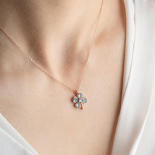 Rose gold necklace with a green gemstone pendant on a person wearing a white top.