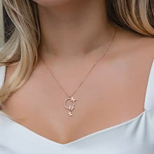 Gold necklace with a pendant worn by a person against a neutral background
