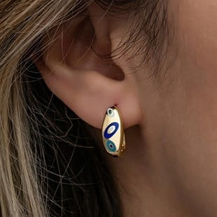 Close-up of an ear wearing a gold earring with blue and green accents.
