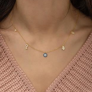 Necklace with various pendants on a person wearing a pink sweater