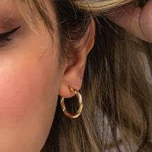 Close-up of a gold hoop earring worn by a person with blonde hair.