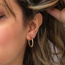 Close-up of a person wearing a gold hoop earring.
