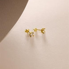 Gold earrings on a beige background