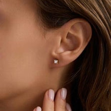 Close-up of a diamond stud earring on an ear with a blurred background