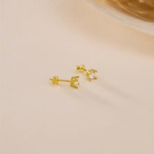 Gold earrings with a small gemstone on a beige background