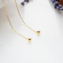 Gold necklace with small round pendants on a white background