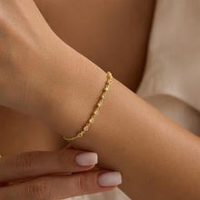 Gold bracelet on a wrist with a neutral background