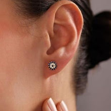 Close-up of an ear wearing a small earring with a decorative design.