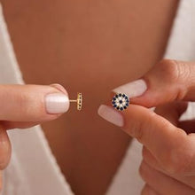 Close-up of two earrings being held, one gold and one black and white.