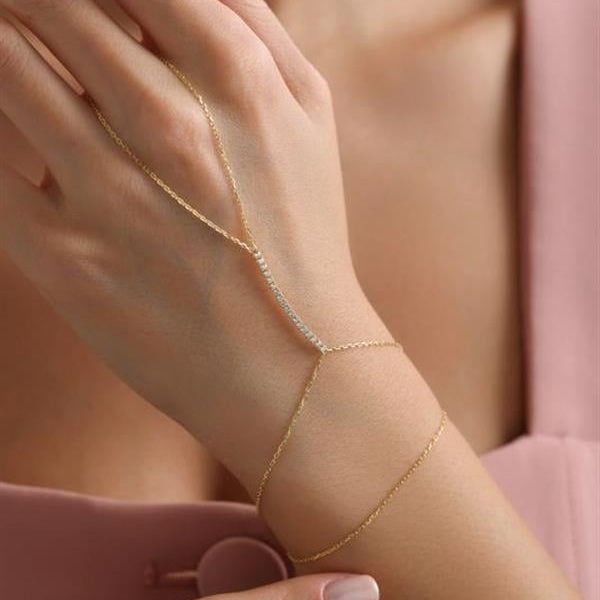 Gold anklet on a person's ankle with a soft pink background