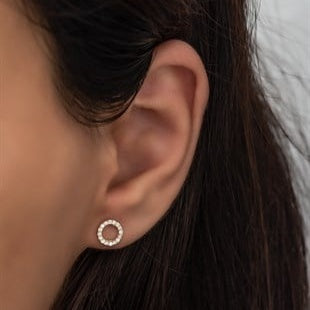 Close-up of an ear wearing a gold hoop earring with dark hair and a neutral background