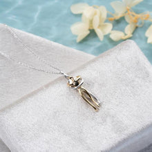 Silver necklace with a unique pendant on a white surface with a light blue background