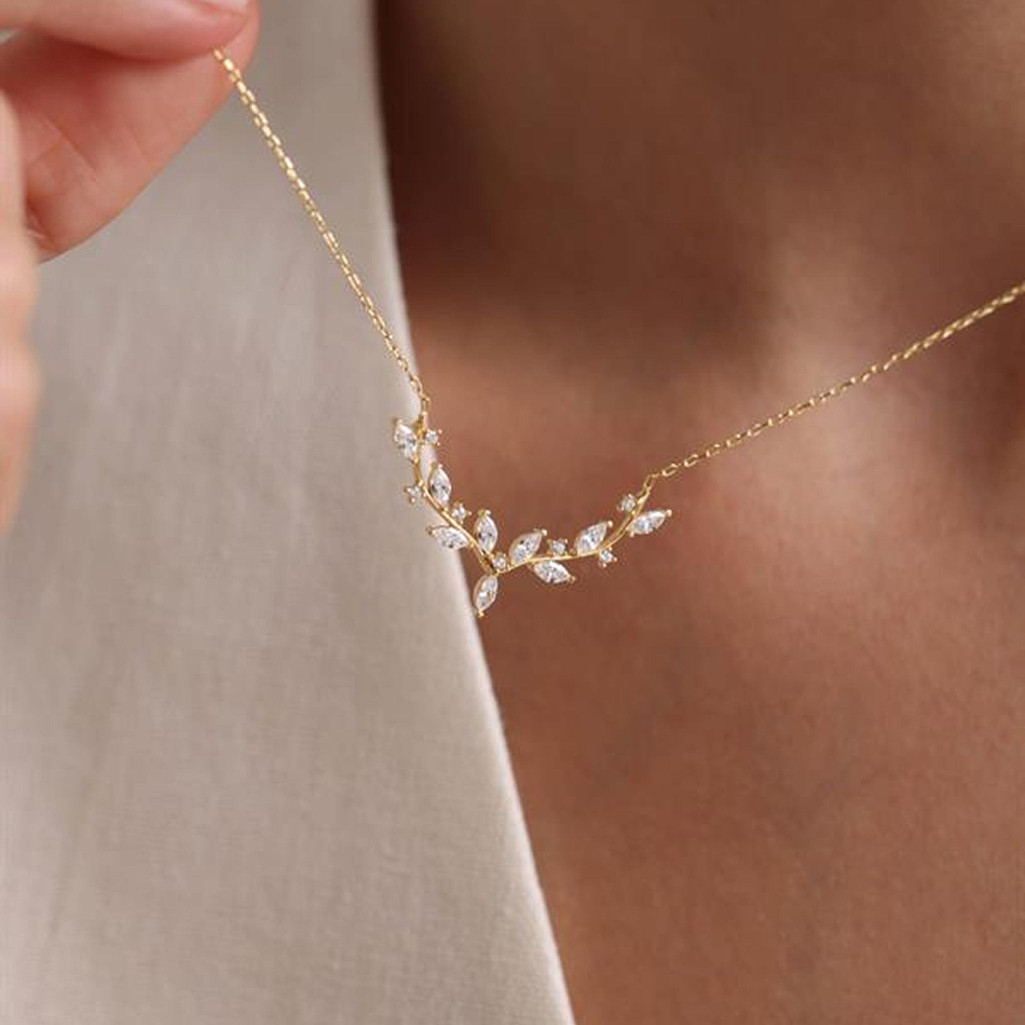 Gold necklace with leaf design worn by a person