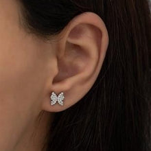 Close-up of an ear wearing a butterfly-shaped diamond earring.