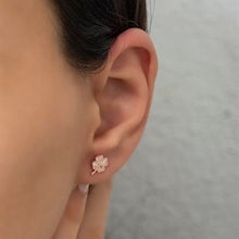 Close-up of an ear wearing a floral earring with a blurred background