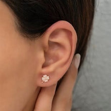 Close-up of an ear wearing a floral earring with a blurred background
