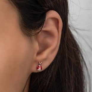 Close-up of an ear wearing a red earring with a small design.