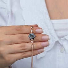 Hand holding a delicate bracelet with a floral clasp against a white background