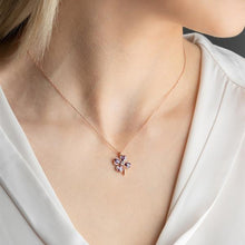 Necklace with a pink flower pendant worn by a person in a white outfit.